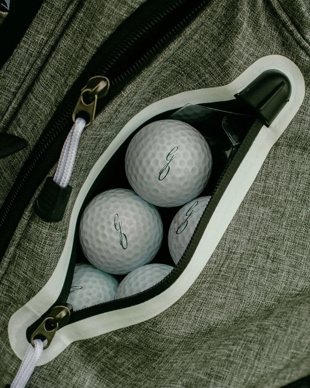Golf balls in the pocket of a grey golf bag