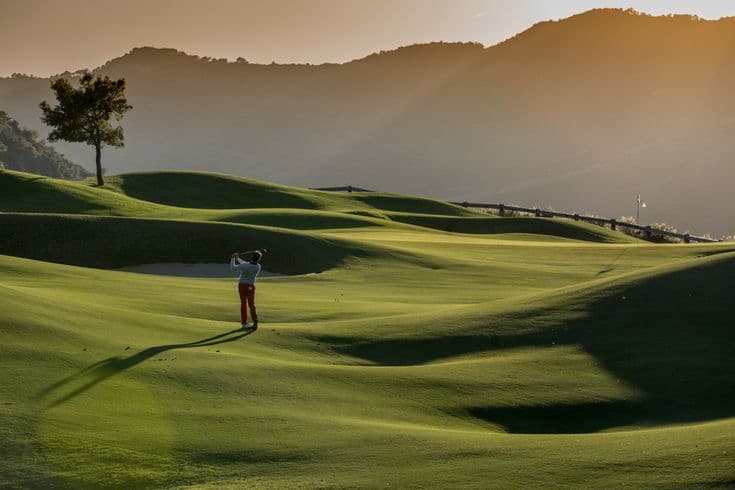 An evening fairway with a golfer mid-swing